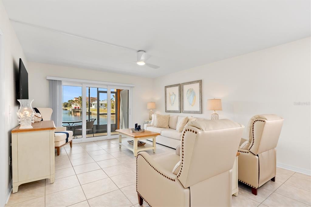 A living room features tile floors, a beige sofa, two armchairs, and a sliding glass door — 1345 MEDITERRANEAN DRIVE UNIT A105, PUNTA GORDA, FL