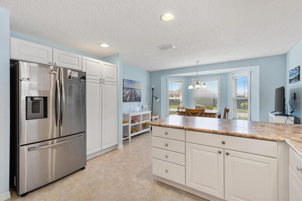 A kitchen with white cabinets, stainless steel appliances, and a dining area with bay windows — 7815 SE 166TH HIBERNIA LANE, THE VILLAGES, FL
