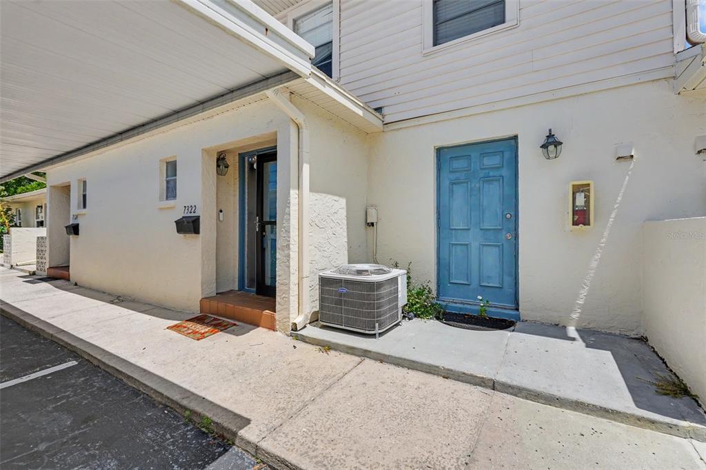 An exterior view of a building with a carport, two entry doors, and an air conditioner — 7322 STONE HAVEN COURT N UNIT 7322, PINELLAS PARK, FL