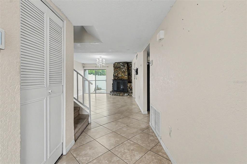 A tiled hallway leads to a living area with a stone fireplace and sliding glass doors — 7322 STONE HAVEN COURT N UNIT 7322, PINELLAS PARK, FL