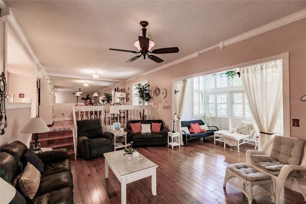 A living room with hardwood floors, a ceiling fan, and an adjacent dining area — 6030 E PEPPERTREE WAY UNIT 222A, SARASOTA, FL
