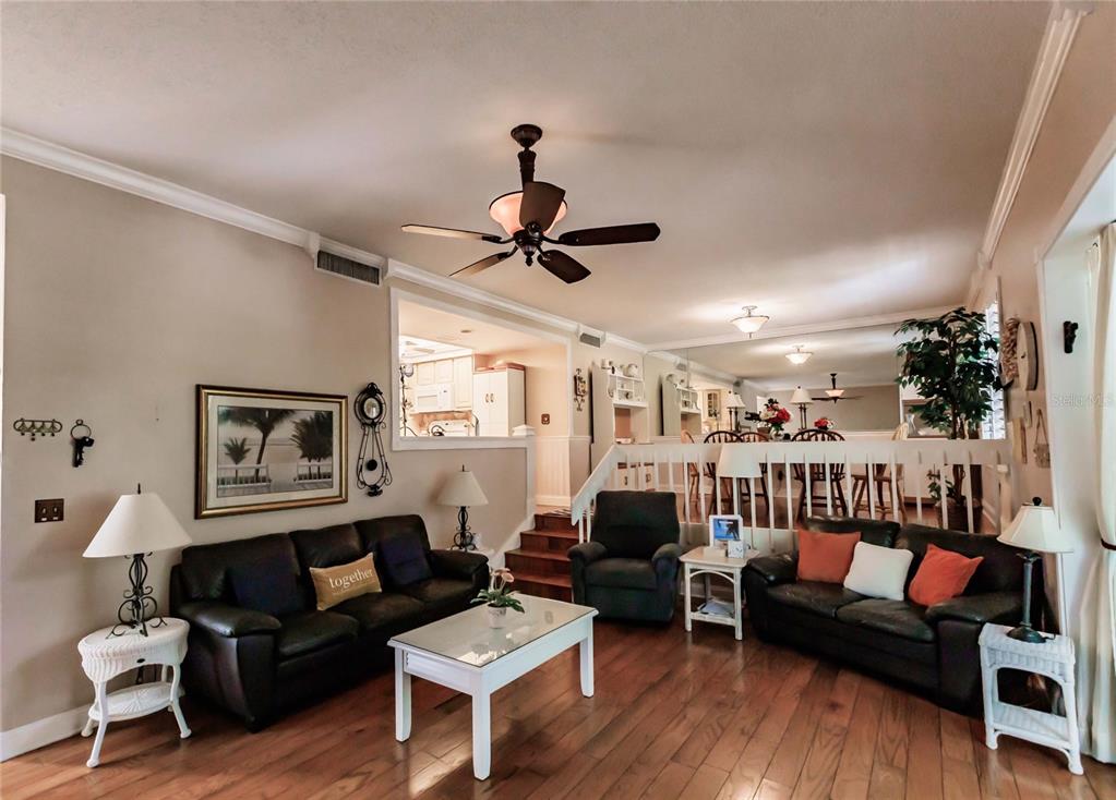 A living room features dark leather sofas, a white coffee table, and wood flooring — 6030 E PEPPERTREE WAY UNIT 222A, SARASOTA, FL