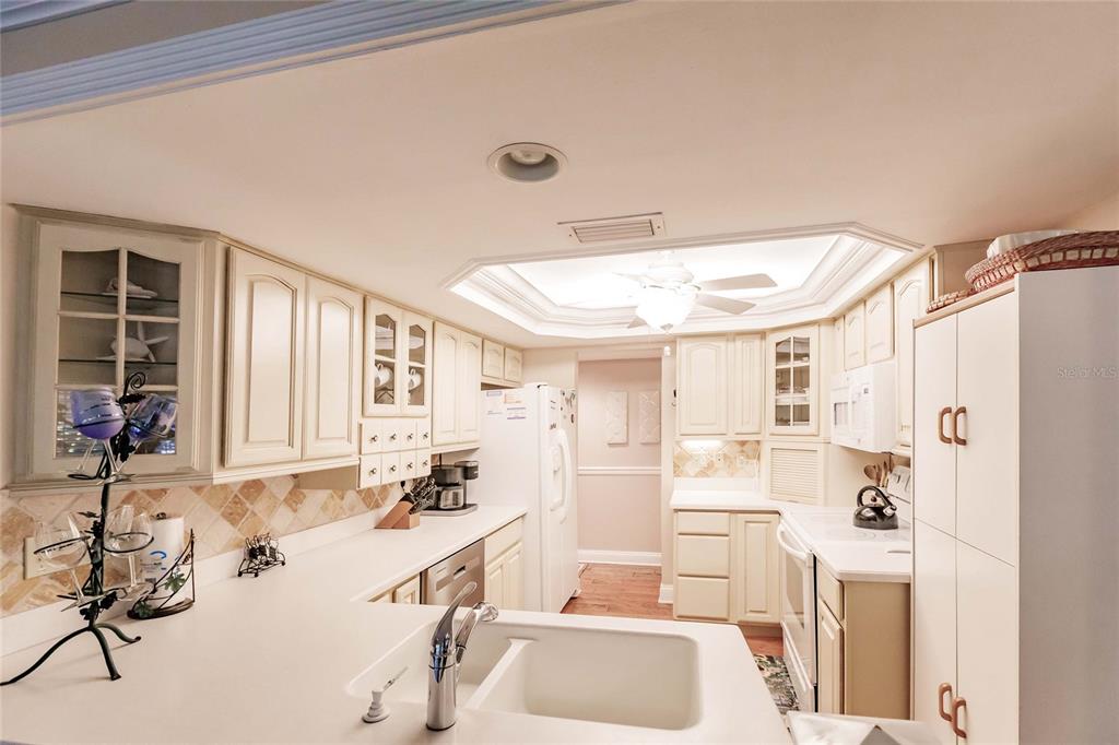 A kitchen with cream-colored cabinets, white countertops, a double sink, and a ceiling fan — 6030 E PEPPERTREE WAY UNIT 222A, SARASOTA, FL