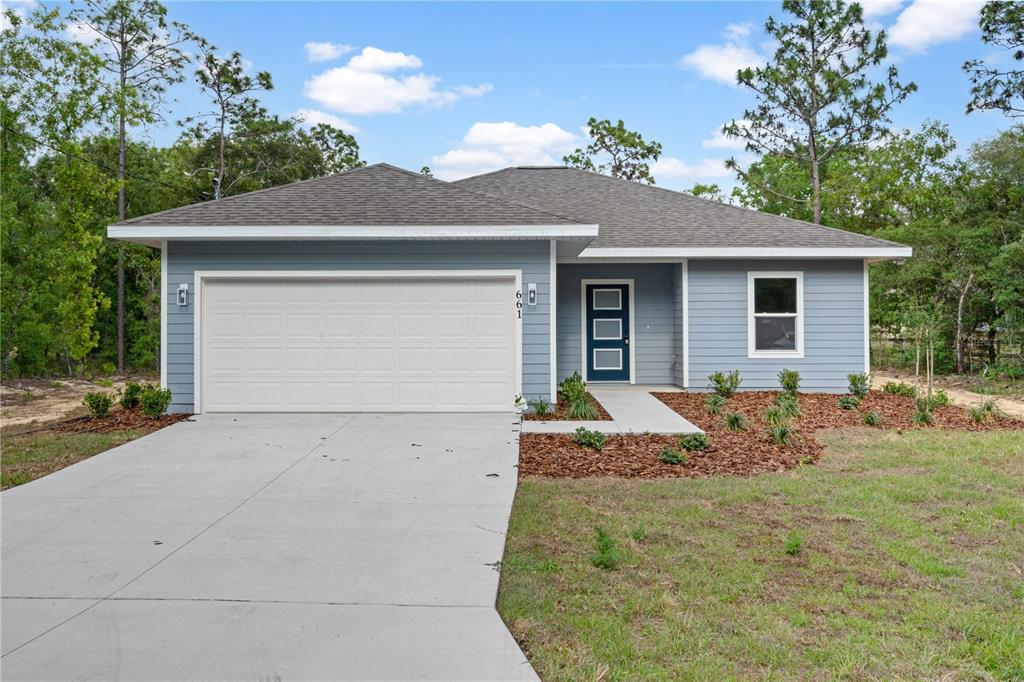 A single-story house with blue horizontal siding, a two-car garage, and a front walkway — 661 NE 150TH COURT, WILLISTON, FL