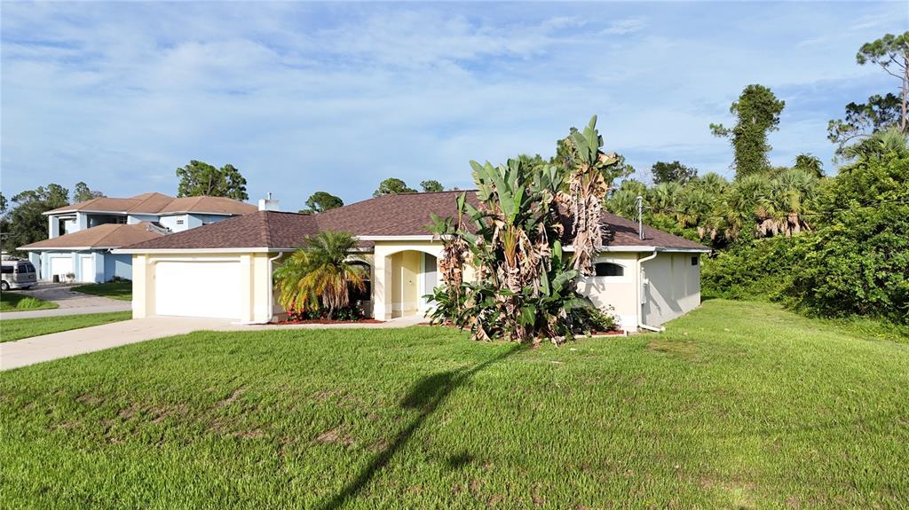 A single-story house with a tan exterior, a brown roof, and large tropical plants — 2991 GRANDVIEW DRIVE, NORTH PORT, FL