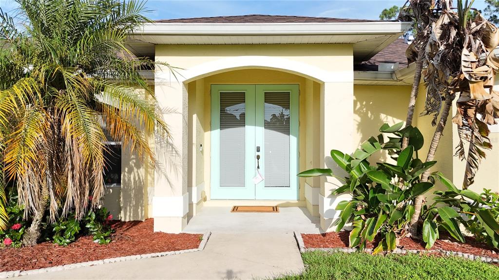 The exterior of a house features a light-colored facade, double front doors, and palm trees — 2991 GRANDVIEW DRIVE, NORTH PORT, FL