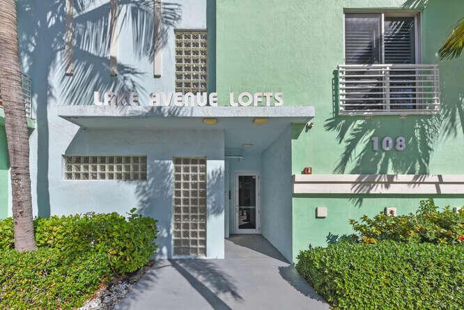 The exterior entrance of a multi-story apartment building features a light blue and green facade — 108 Lake Avenue # 406, FL 33460, FL