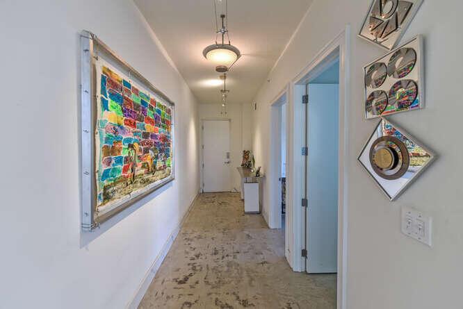 A hallway features a large framed artwork on the left, decorative wall mirrors, and concrete flooring — 108 Lake Avenue # 406, FL 33460, FL