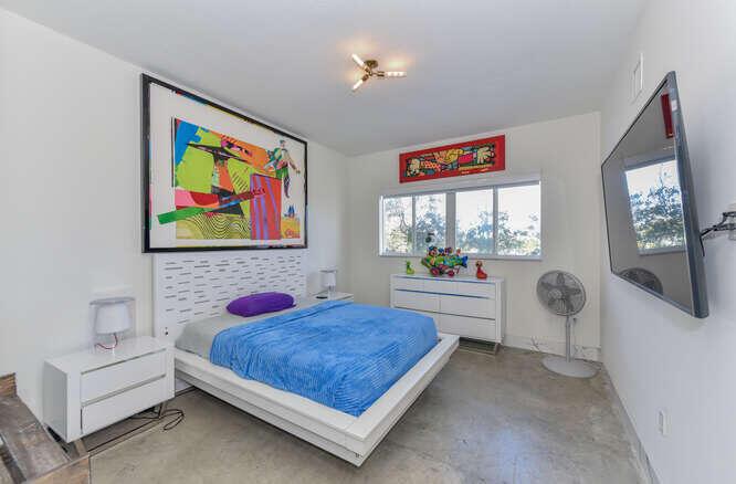 A bedroom features a platform bed, white furniture, colorful wall art, and a wall-mounted television — 108 Lake Avenue # 406, FL 33460, FL