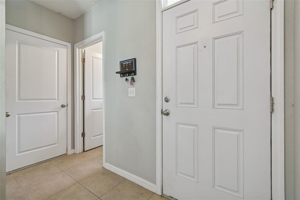 An entryway features tiled flooring, light gray walls, two interior doors, and a front door — 10104 HAWK STORM AVENUE, TAMPA, FL