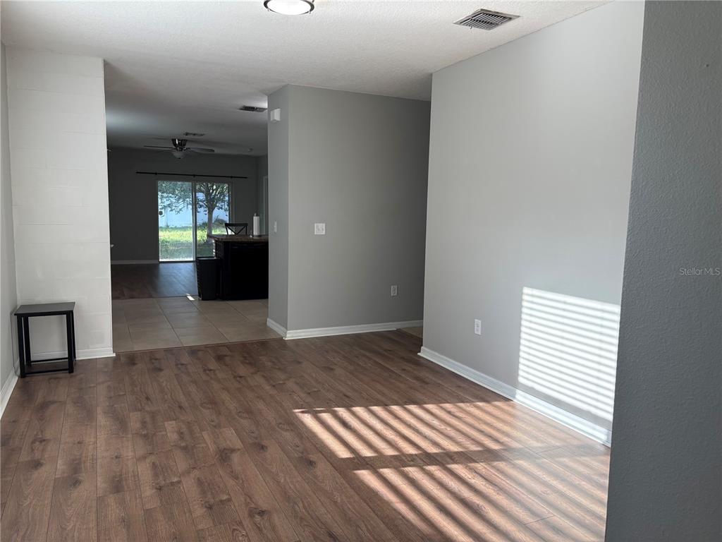 An interior view shows a living area with wood-look flooring leading to a tiled kitchen — 10104 HAWK STORM AVENUE, TAMPA, FL