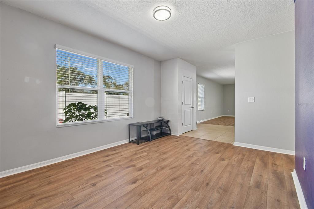 A room with light gray walls, wood-look flooring, a window with blinds, and a doorway — 10104 HAWK STORM AVENUE, TAMPA, FL