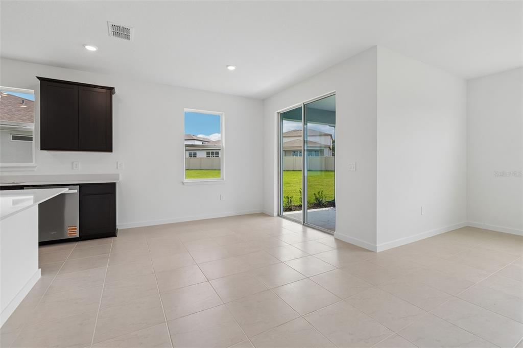 A kitchen and dining area with tile flooring, dark cabinets, and a sliding glass door — 11243 SYCAMORE GLEN LOOP, THONOTOSASSA, FL