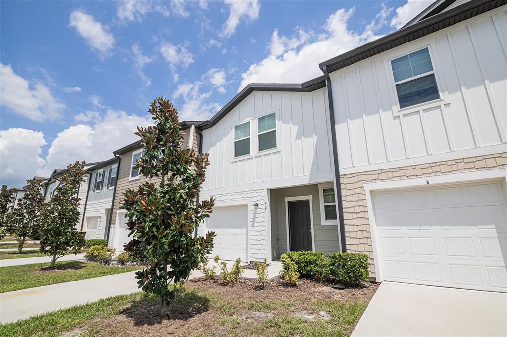 A row of two-story townhomes with white vertical siding, shingle accents, and attached garages — 529 MADISON DRIVE, DAVENPORT, FL
