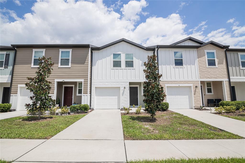 A row of three modern townhomes features varied siding, attached garages, and small front lawns — 529 MADISON DRIVE, DAVENPORT, FL