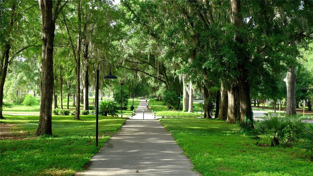 A paved walking path winds through a lush, tree-lined park with hanging Spanish moss — 13327 SW 9TH ROAD, NEWBERRY, FL