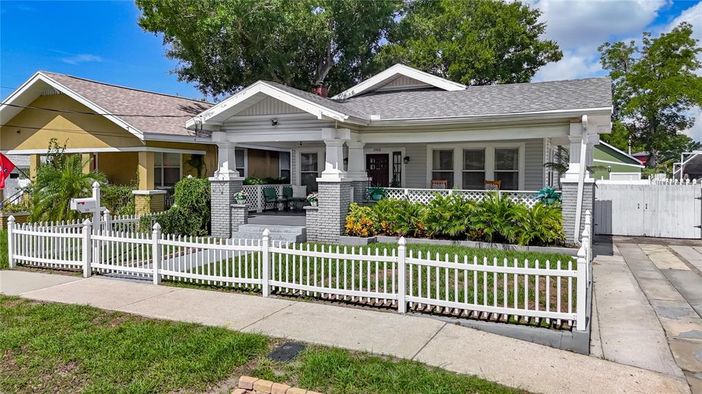 A gray bungalow with a covered front porch and white picket fence under a blue sky — 3506 N 12TH STREET, TAMPA, FL