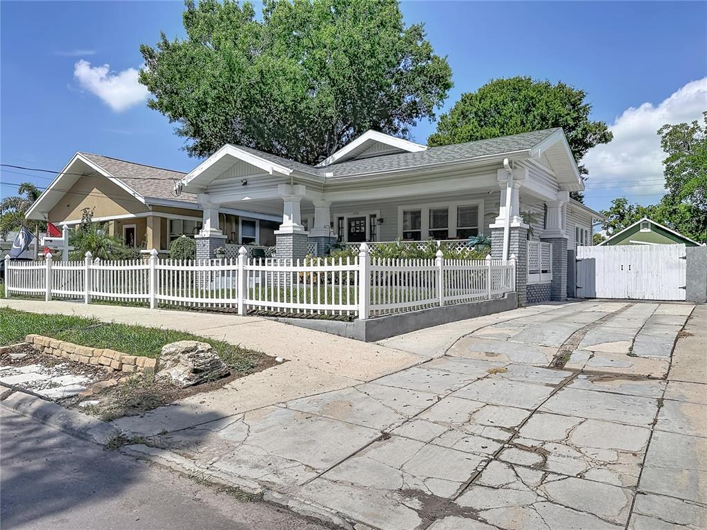 A light-colored bungalow with a front porch and white picket fence sits on a street — 3506 N 12TH STREET, TAMPA, FL