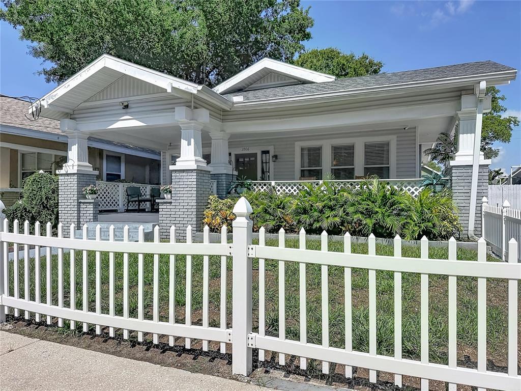 A light gray bungalow with a covered front porch and a white picket fence — 3506 N 12TH STREET, TAMPA, FL