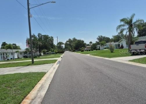 A paved residential street stretches forward with houses, lawns, and trees on both sides — 639 N 75TH AVENUE N, ST PETERSBURG, FL
