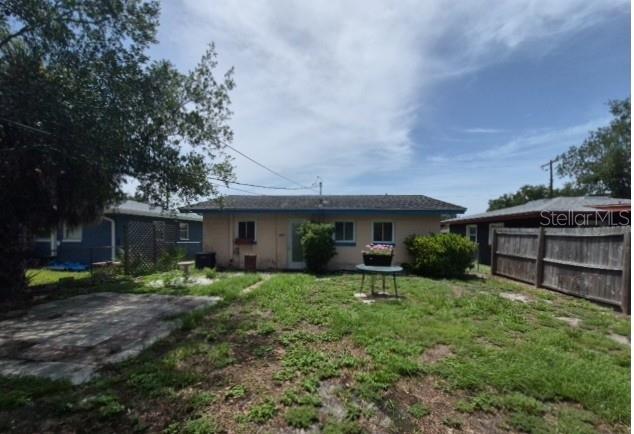 A backyard view of a single-story house with a lawn, patio, and wooden fence — 639 N 75TH AVENUE N, ST PETERSBURG, FL