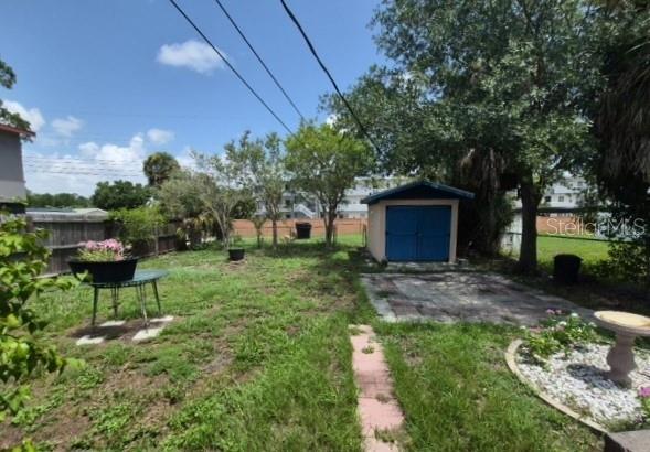 A backyard features a small shed, a patio, a stone birdbath, and a metal table — 639 N 75TH AVENUE N, ST PETERSBURG, FL