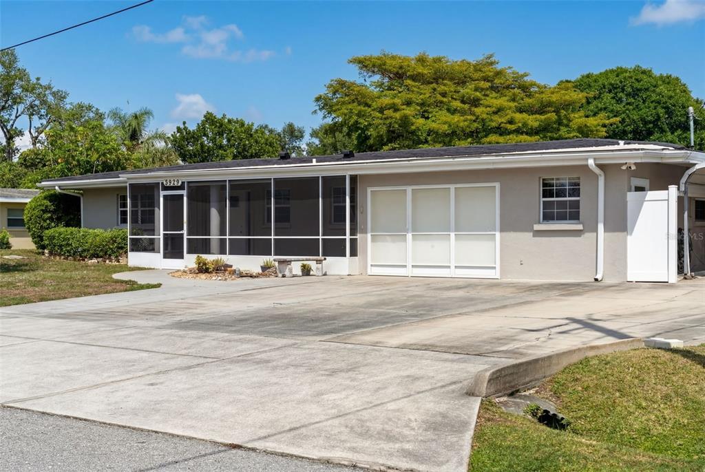 A single-story house with a screened-in porch and a concrete driveway under a blue sky — 5929 MURDOCK AVENUE, SARASOTA, FL