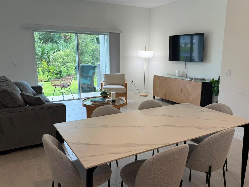 A dining area and living room feature a marble-topped table, gray sofa, and sliding doors — 3119 SKYLINE LOOP, POINCIANA, FL