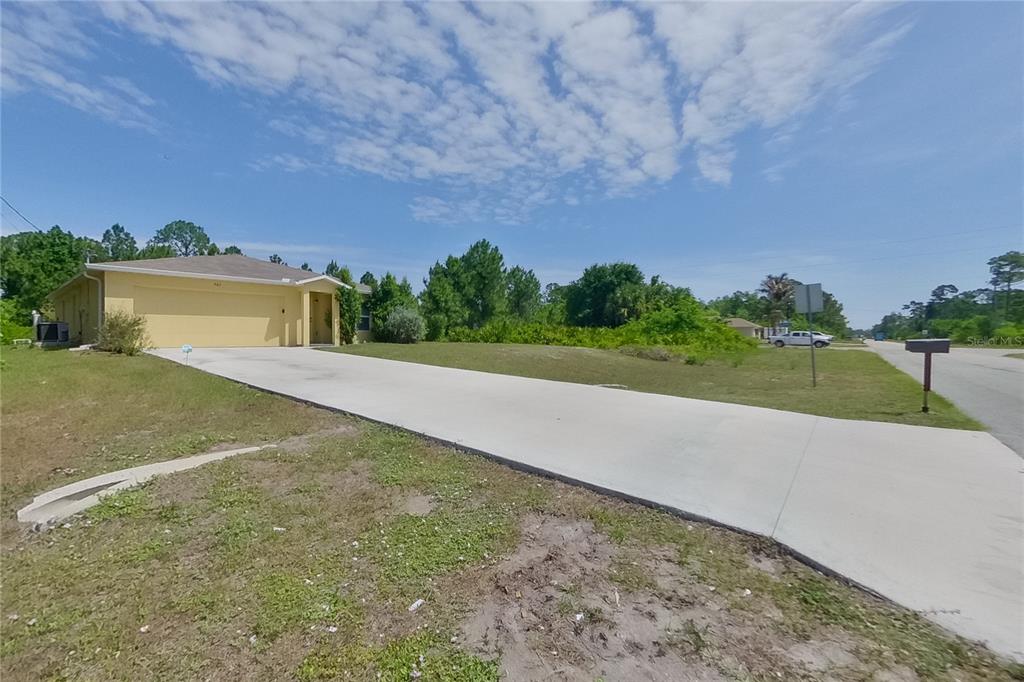 A yellow single-story house with a concrete driveway sits on a grassy lot — 947 GRANT BOULEVARD, LEHIGH ACRES, FL