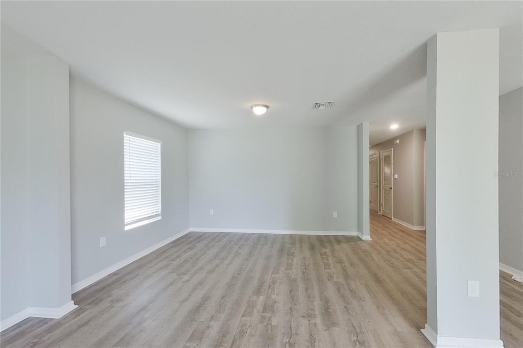 An empty room with light gray walls, wood-look flooring, and a single window — 947 GRANT BOULEVARD, LEHIGH ACRES, FL