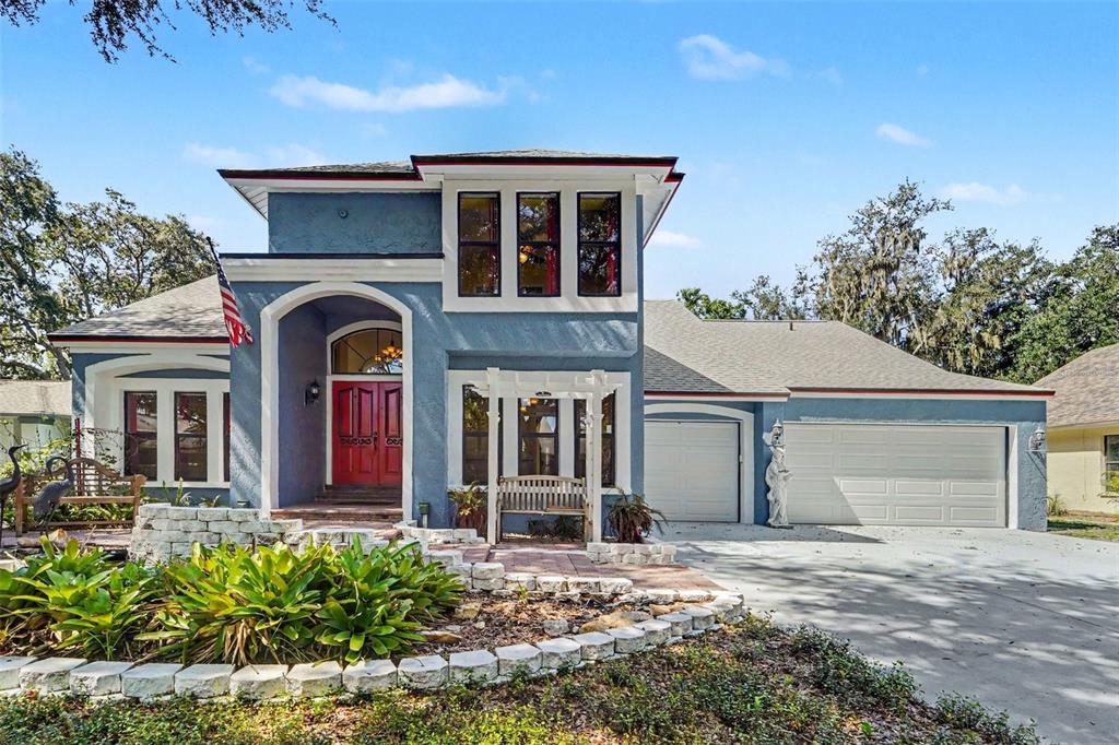 A two-story blue house with a red front door, three-car garage, and landscaped front yard — 6203 FARTHING STREET, TAMPA, FL