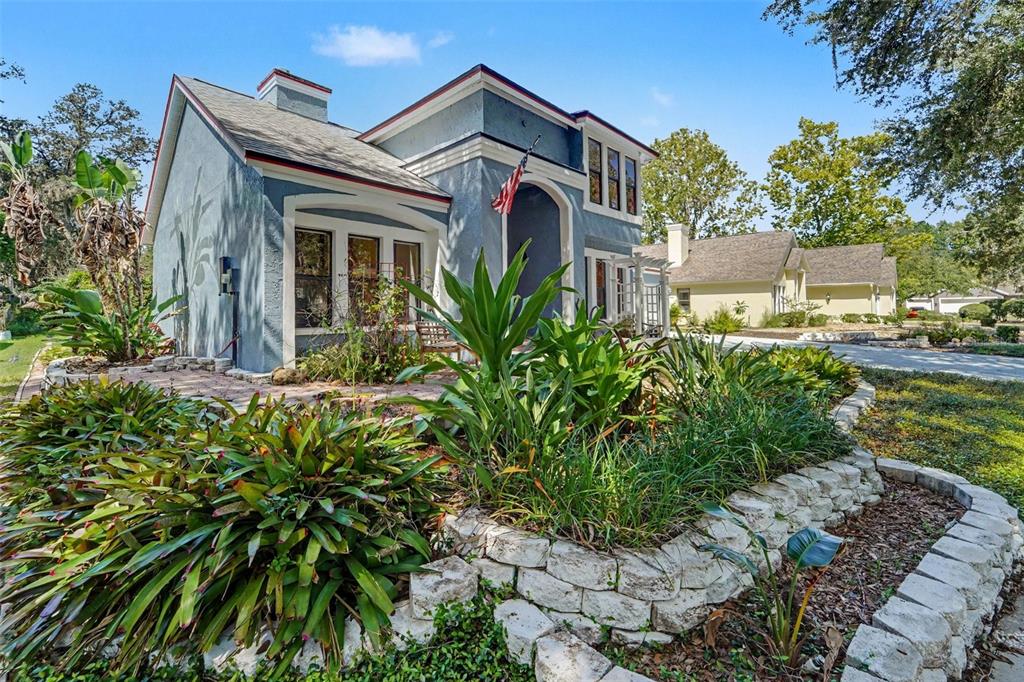 A blue house with a stone retaining wall and lush landscaping in the front yard — 6203 FARTHING STREET, TAMPA, FL