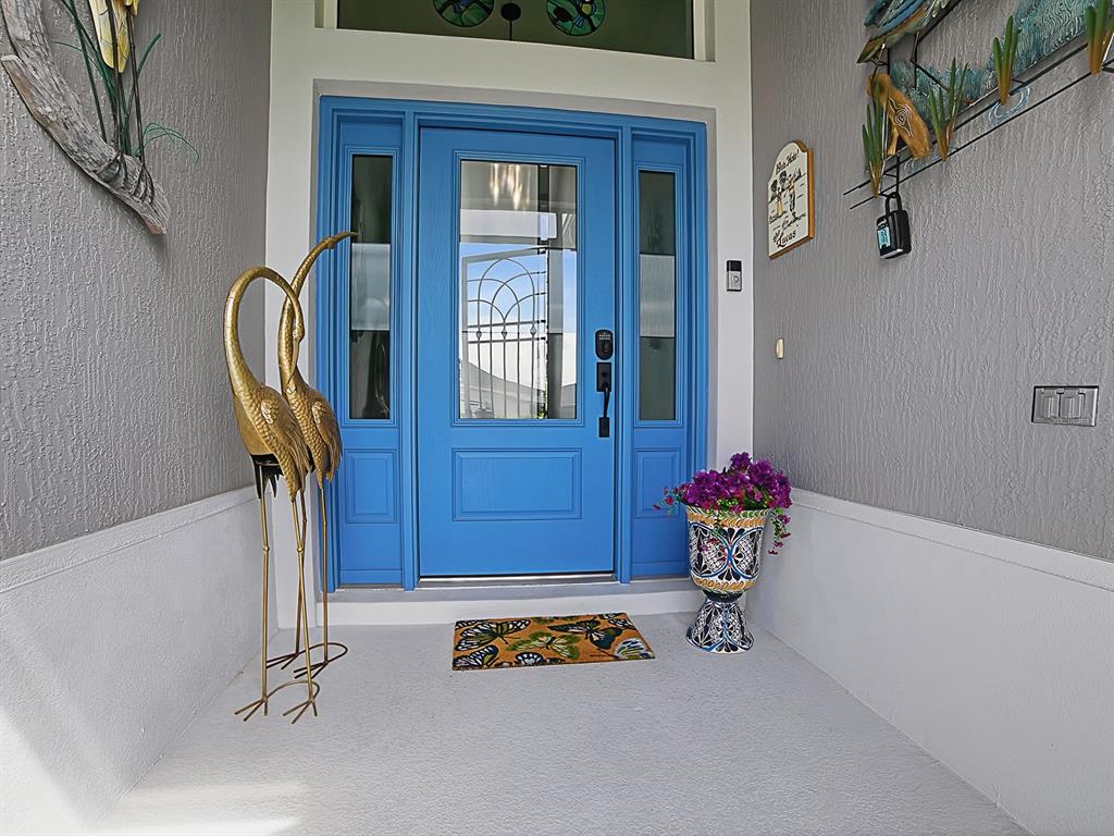 A bright blue front door with sidelights is framed by gray walls and coastal decor — 7004 EMILINE TERRACE, THE VILLAGES, FL