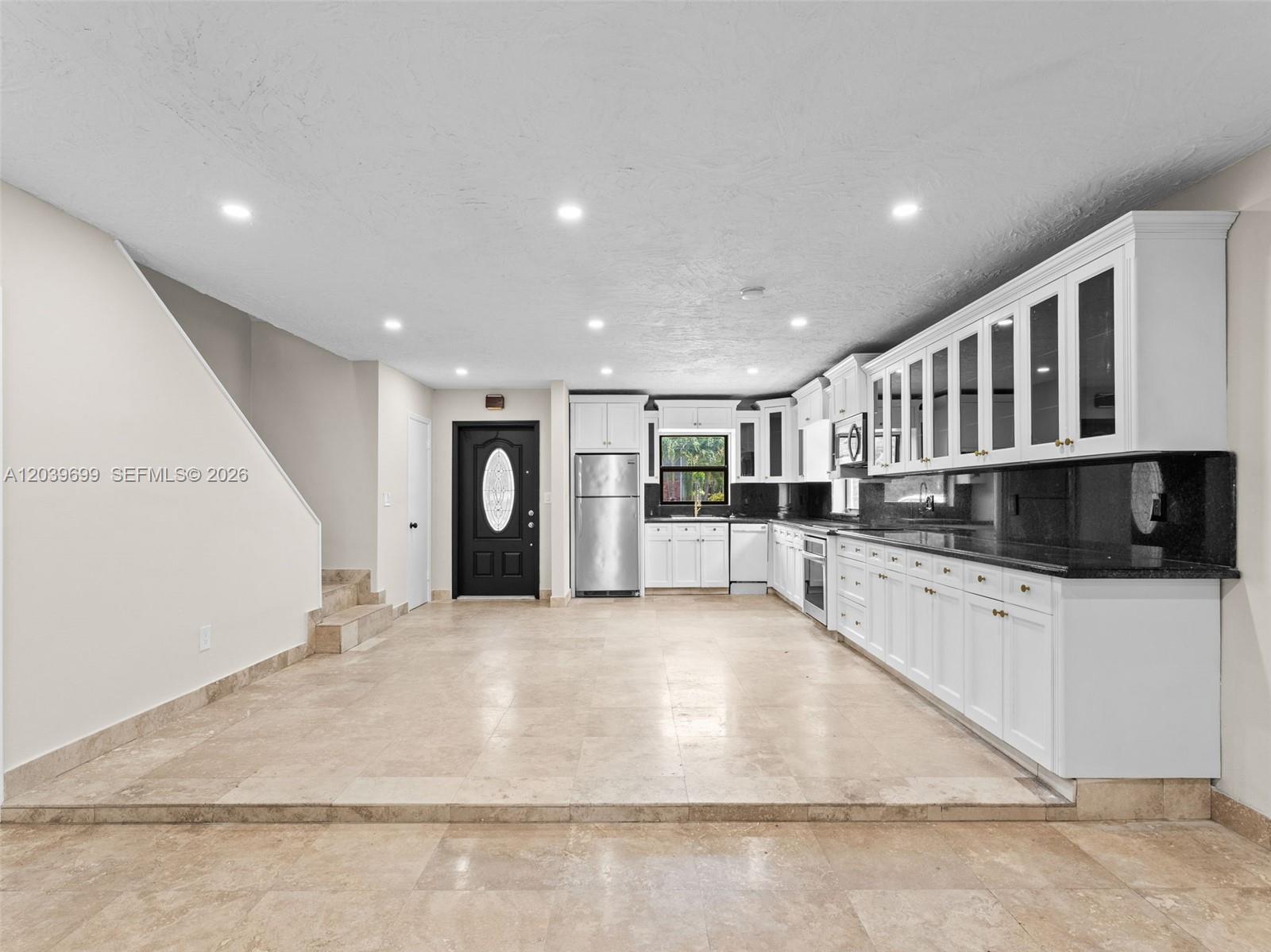 A kitchen with white cabinets, black countertops, and a raised tiled floor area — 13502 NE 24th Ct, North Miami FL 33181, NORTH MIAMI, FL