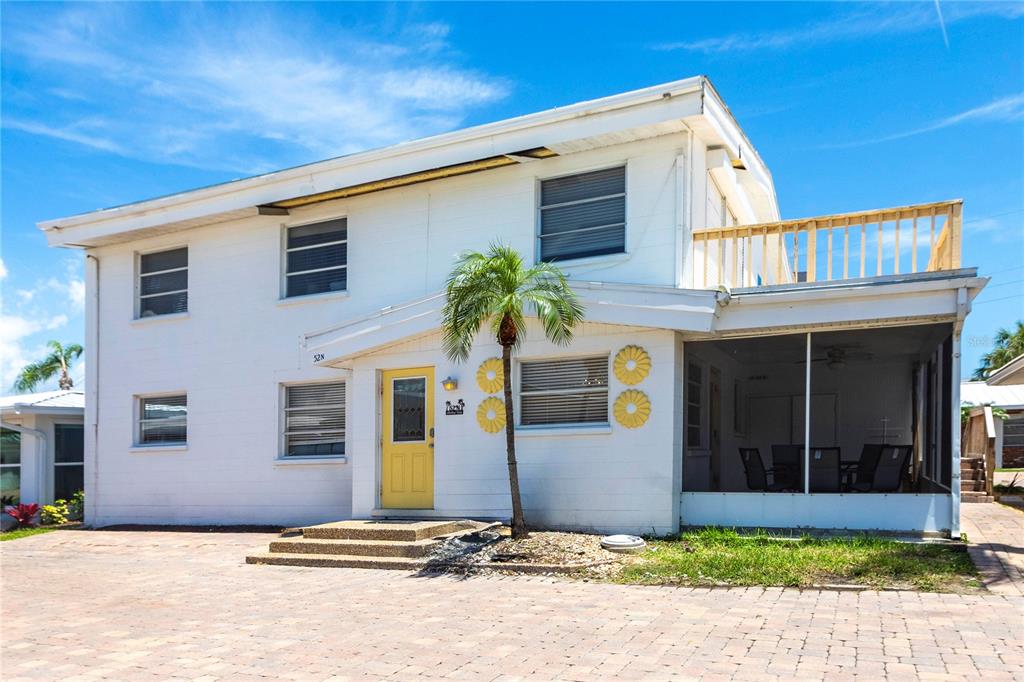A two-story white house with a yellow front door, a palm tree, and a screened porch — 6020 MIDNIGHT PASS ROAD UNIT 52B, SARASOTA, FL