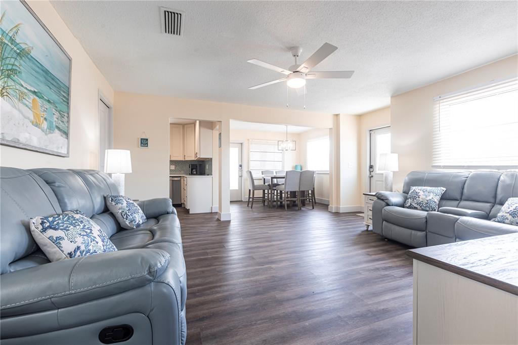 A living room with light blue leather sofas, wood-look flooring, and an adjacent dining area — 6020 MIDNIGHT PASS ROAD UNIT 52B, SARASOTA, FL