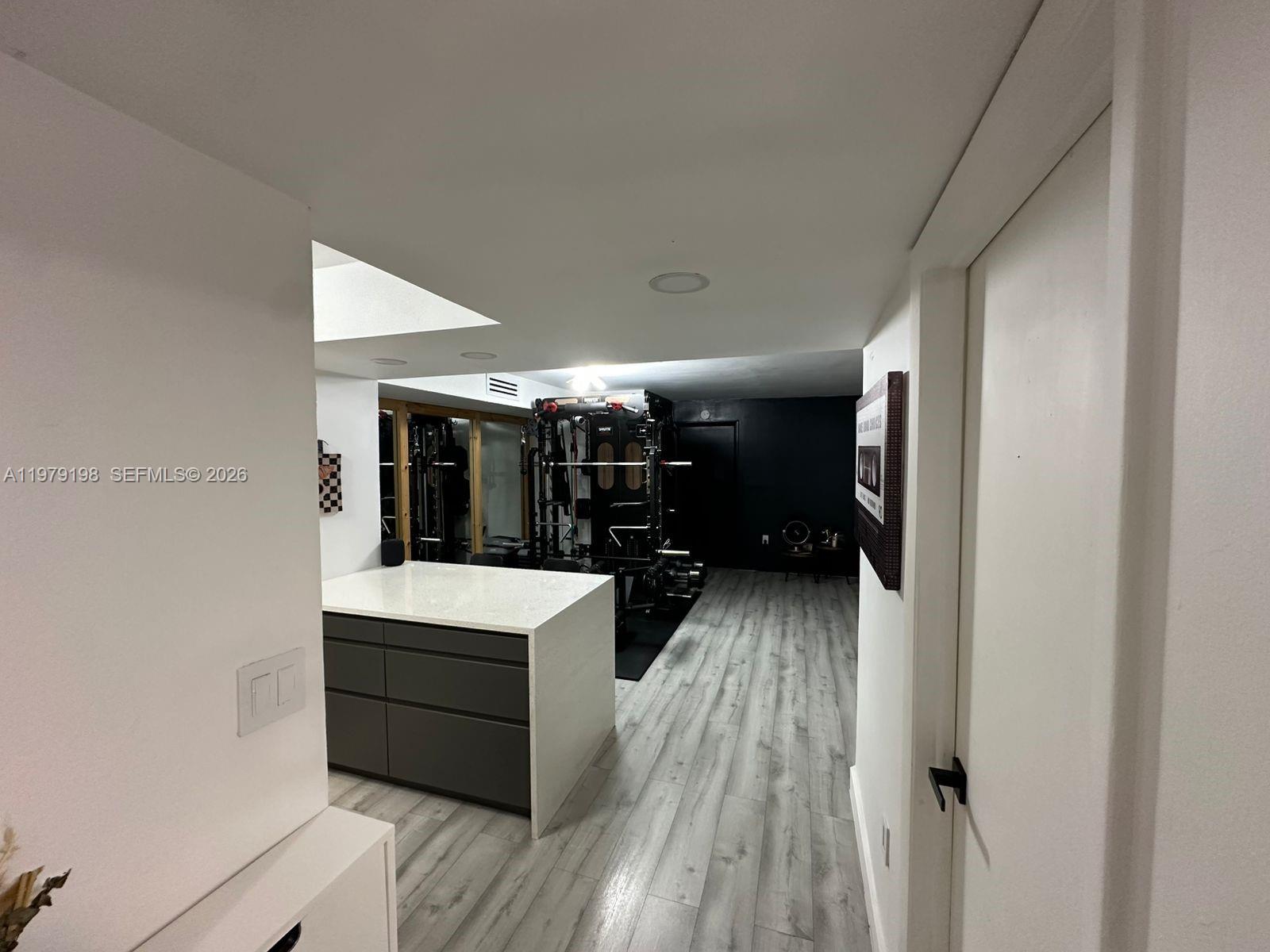 A home gym features a weight rack, a kitchen island, and light wood-look flooring — 931 NE 199th St # 22, Miami FL 33179, MIAMI, FL