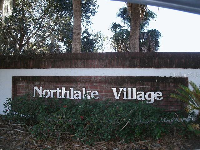 A brick wall sign displays the name Northlake Village in front of trees and bushes — 208 NORTHLAKE DRIVE UNIT 208, SANFORD, FL