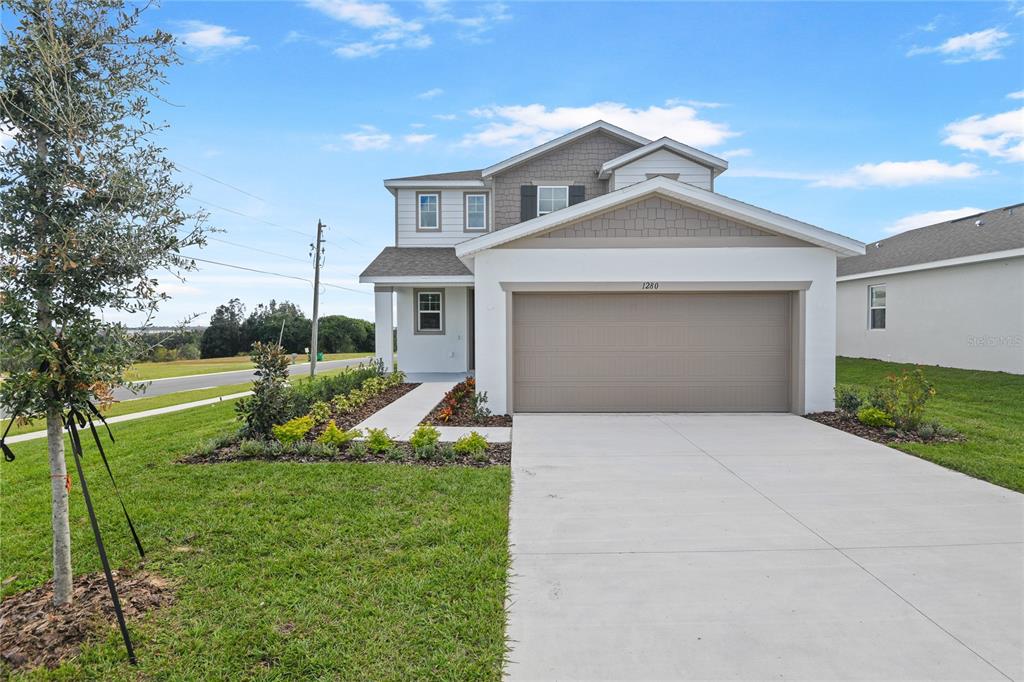 A two-story house with a white stucco facade, gray garage door, and a concrete driveway — 1280 DAISY HILL AVENUE, DUNDEE, FL