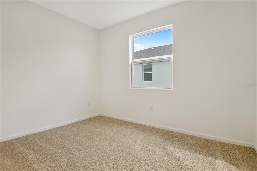 An empty bedroom features beige carpet, white walls, and a single window — 1280 DAISY HILL AVENUE, DUNDEE, FL