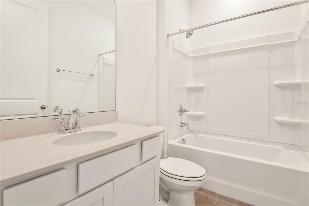 A bathroom features a white vanity, a mirror, a toilet, and a shower-tub combination — 1280 DAISY HILL AVENUE, DUNDEE, FL