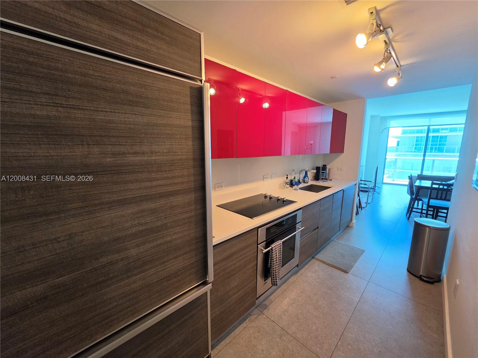 A modern kitchen features bright red upper cabinets, dark wood lower cabinets, and a stainless sink — 1100 S Miami Ave # 3705, Miami FL 33130, MIAMI, FL