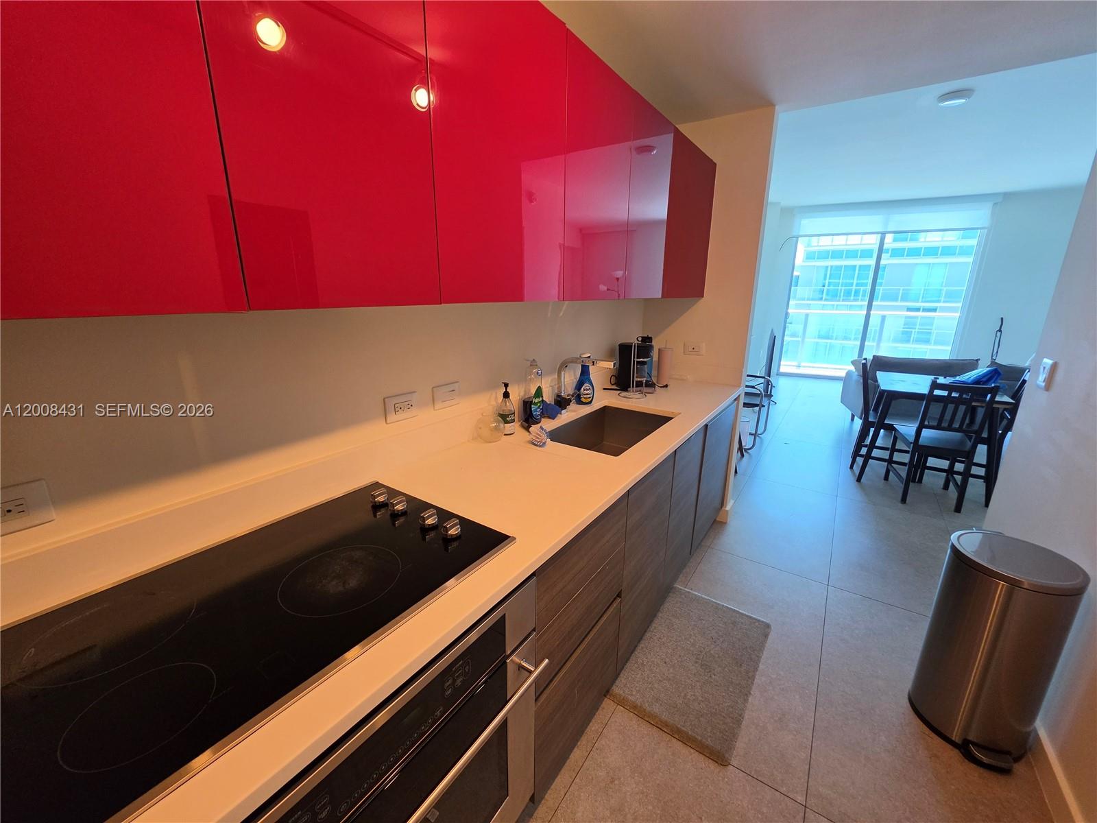 A kitchen features bright pink upper cabinets, wood-toned lower cabinets, and light gray floor tiles — 1100 S Miami Ave # 3705, Miami FL 33130, MIAMI, FL