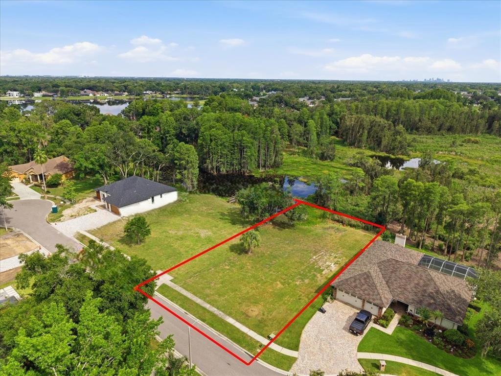 An aerial view shows a vacant rectangular residential lot outlined in red between two houses — WOODS END CT, TAMPA, FL