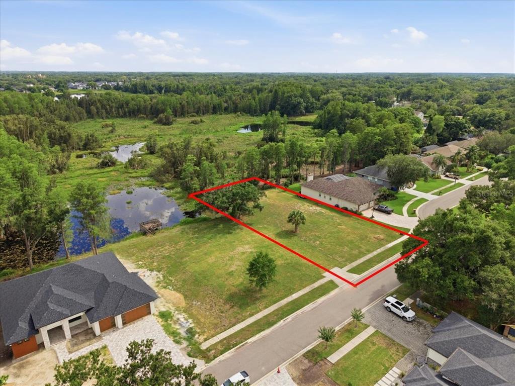 An aerial view shows a vacant residential lot outlined in red next to a pond — WOODS END CT, TAMPA, FL