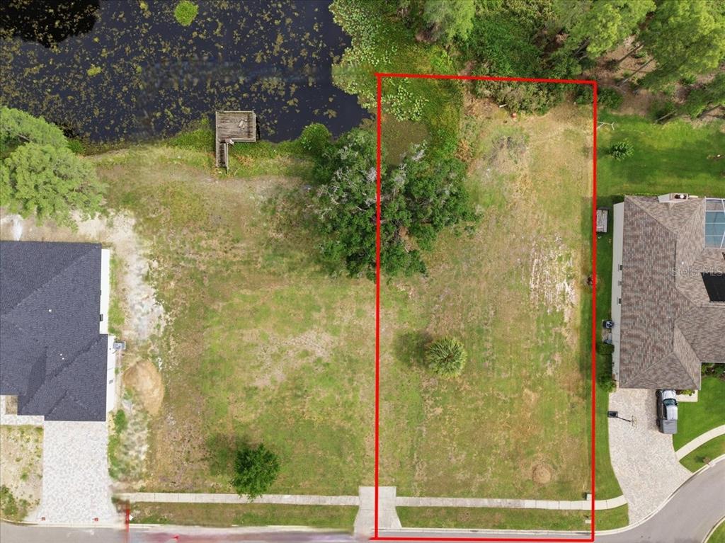 An aerial view shows a vacant, rectangular residential lot situated between two houses and a lake — WOODS END CT, TAMPA, FL