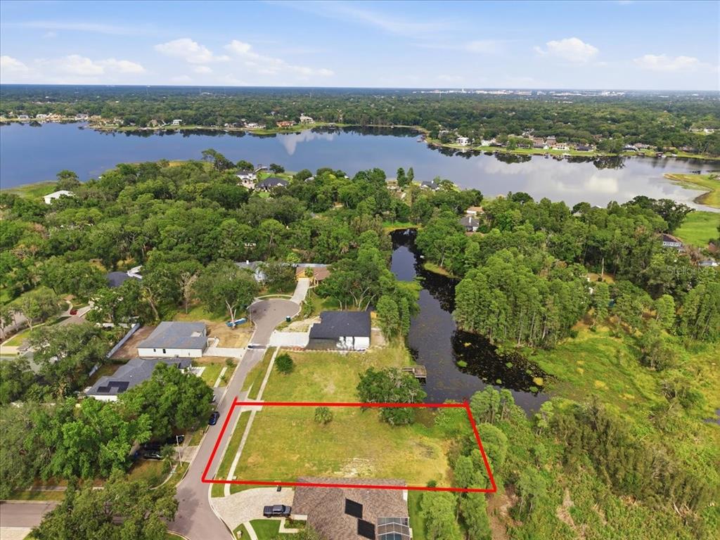 An aerial view shows a vacant residential lot outlined in red next to a pond — WOODS END CT, TAMPA, FL