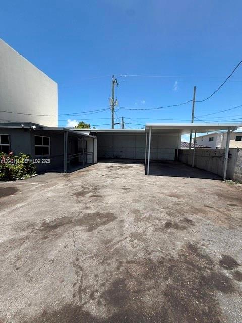 A paved parking area sits in front of a building with a covered carport — MIAMI, FL