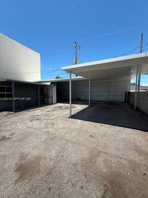 A paved outdoor area features a covered carport structure adjacent to a building exterior — MIAMI, FL