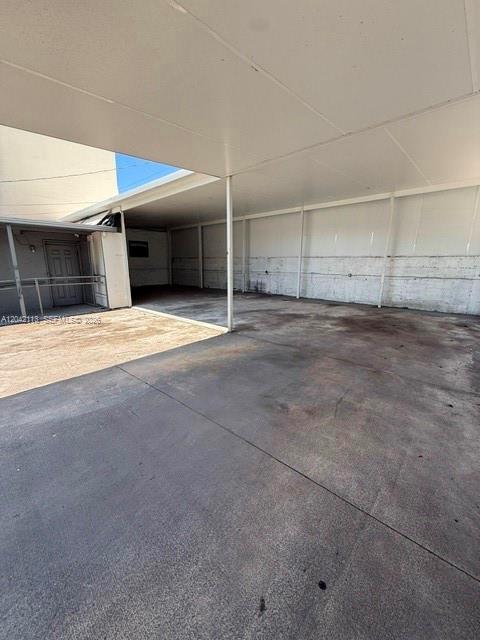 A large, covered concrete parking area features a white ceiling and a metal support structure — MIAMI, FL